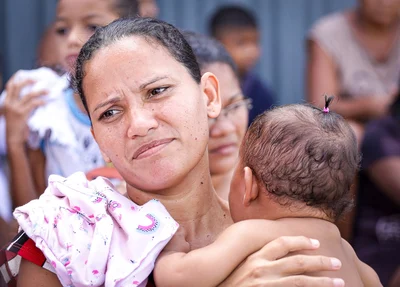 Mãe leva filho a pé com bebê no colo