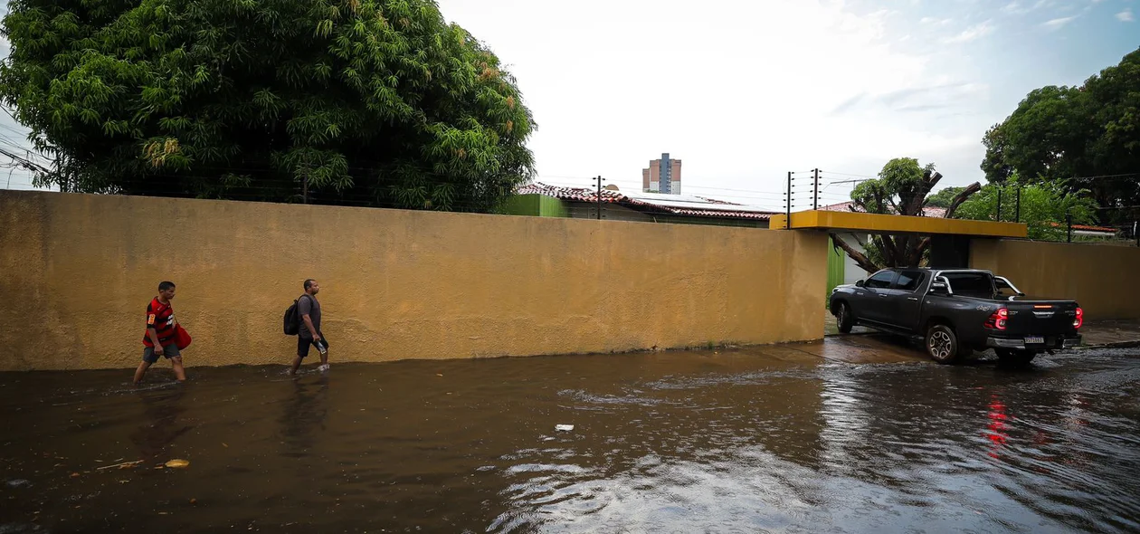 Pedestres caminhando em rua alagada