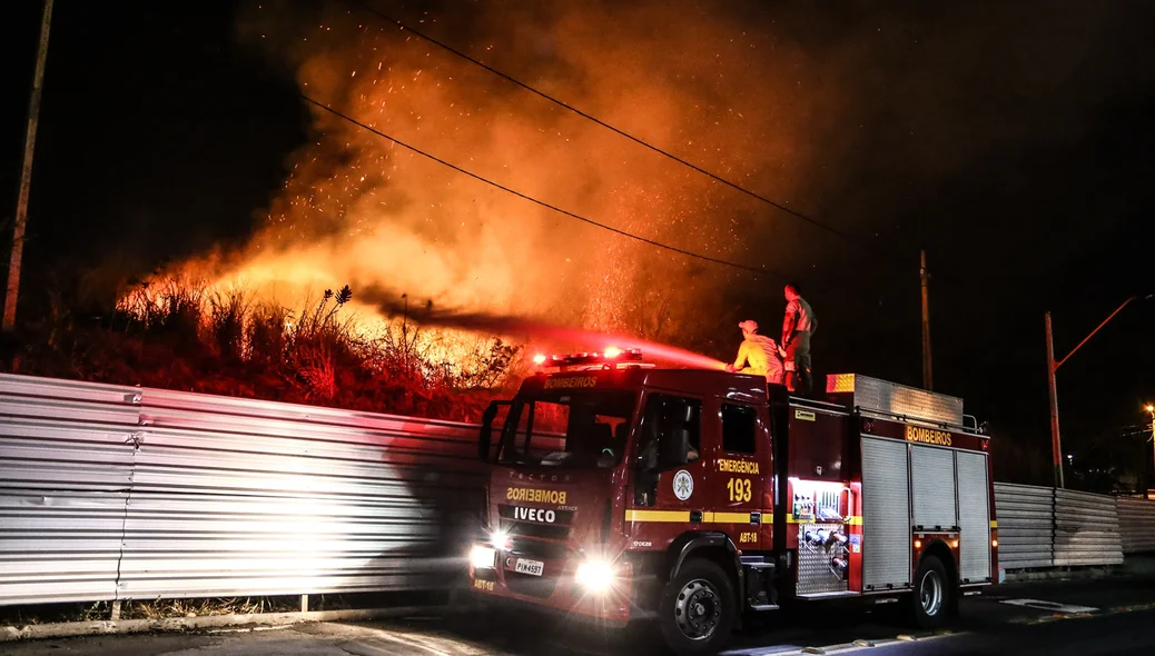 Bombeiros tentando conter o fogo no terreno